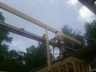 Carpenter setting a ridge beam over a new addition frame in Harborcreek