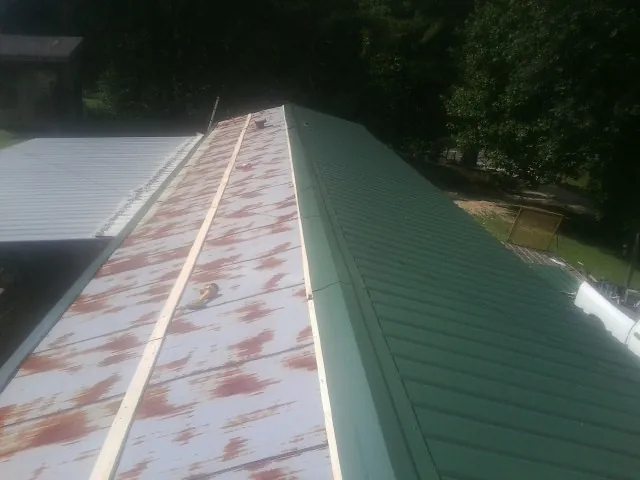 Old rusted panels beside newly installed green metal roofing — Wind Damage Roof Repair by Roofing Brothers in Harborcreek