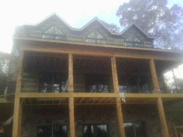 Dormers and porch framing on a large log home under construction — Roof Coating work by our crew in Harborcreek
