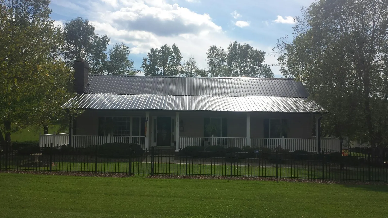 Gray metal roof on a brick ranch with a full width front porch — Gutter Guard Installation work by our crew in Harborcreek