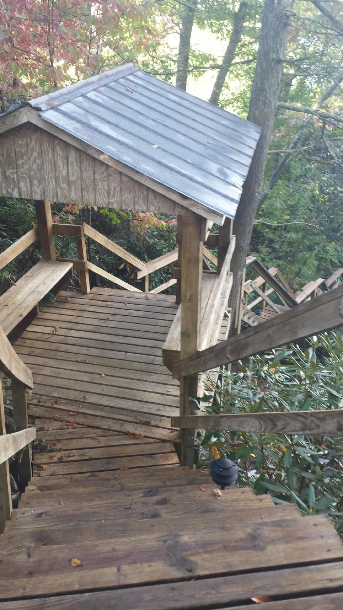 Metal roofed shelter over wooden steps on a wooded walkway — Skylight Repair & Installation work by our crew in Harborcreek